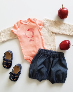 hand dyed, screen printed red apple bodysuit flatlay with indigo denim bloomers and natural sweater
